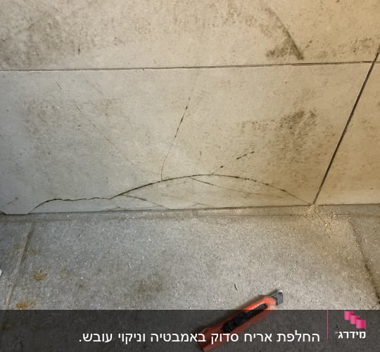 אריחים סדוקים עם סכין חיתוך על הרצפה